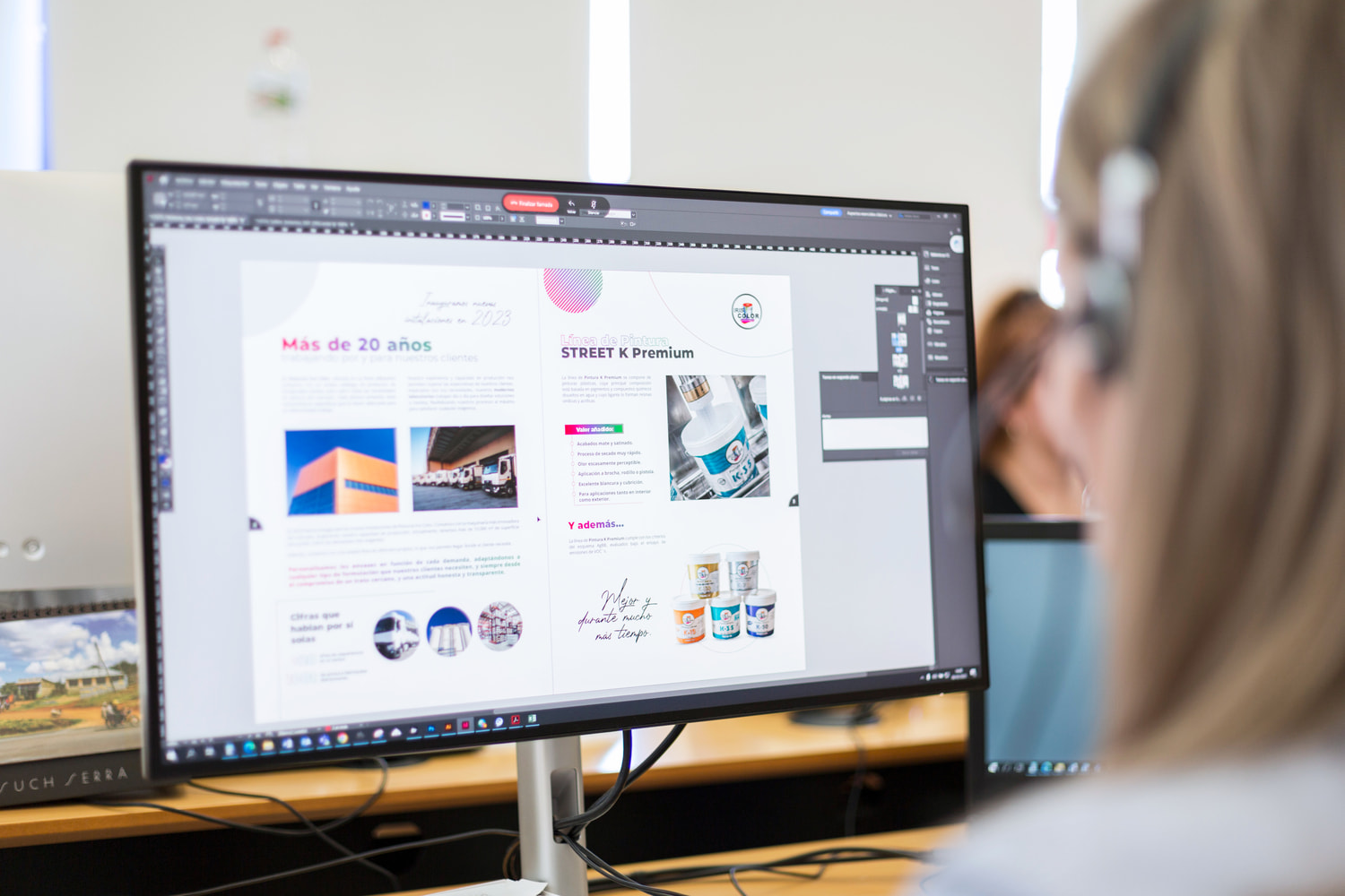 Viewing a woman from behind while she is sitting in front of a computer and looking at an interactive brochure on the screen.